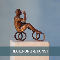 Bronzeplastik von Adelbert Heil: ein Mann sitzt auf vier Ringen