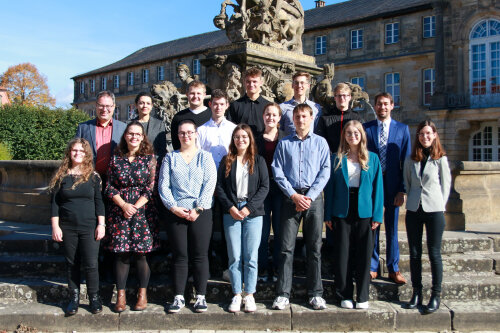 13 neu ernannte Regierungsinspektorinnen und Regierungsinspektoren mit Regierungspräsident Florian Luderschmid (links oben), dem Präsidenten des Verwaltungsgerichts Bayreuth Dr. Thomas Weber (2. von rechts) und Ausbildungsleiterin Barbara Endesfelder (rechts unten)