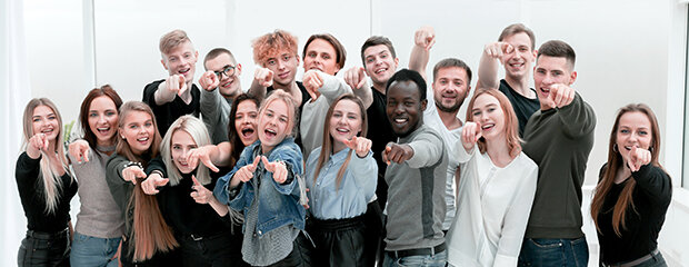 Symbolfoto: Viele junge, lachende Menschen zeigen mit dem Finger auf den Betrachter