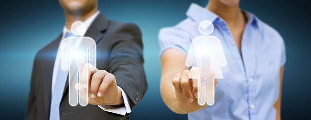 Symbolfoto: Ein Mann und eine Frau in Büro-Outfits tippen auf ihr jeweiliges digitales Mann bzw. Frau-Icon 