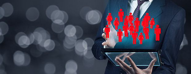 Symbolfoto für Organisation: Mann mit Anzug hält ein Tablet, das ganz viele Personen-Icons anzeigt